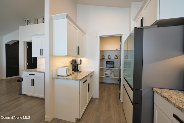 5987 W Quinn Way, Rathdrum, ID 83858 - kitchen with freestanding refrigerator, wood finished floors, white cabinets, light stone counters, and a high ceiling