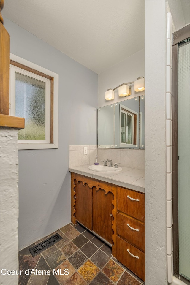 1502 N Melrose St, Coeur Dalene, ID 83814 - bathroom with vanity, stone tile floors, and tasteful backsplash