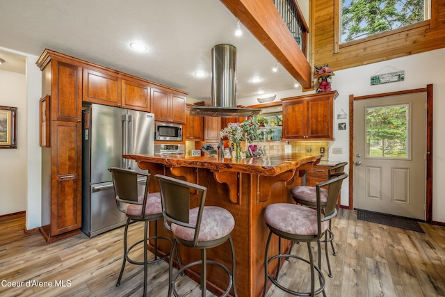 306 Scranton Ave, Coolin, ID 83821 - kitchen with stainless steel appliances, island exhaust hood, light wood-type flooring, a kitchen breakfast bar, and a kitchen island