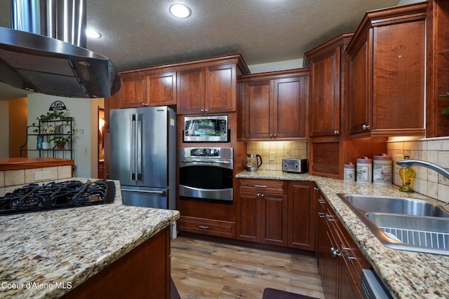 306 Scranton Ave, Coolin, ID 83821 - kitchen with appliances with stainless steel finishes, ventilation hood, light wood finished floors, a textured ceiling, and backsplash