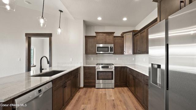 3306 Goodman Dr, Sandpoint, ID 83864 - kitchen with appliances with stainless steel finishes, light wood-style flooring, light stone counters, a peninsula, and backsplash