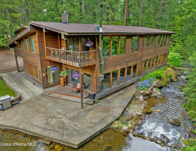 19565 N Goelzer Way, Rathdrum, ID 83858 - back of property with a forest view, a balcony, a patio, a metal roof, and a chimney