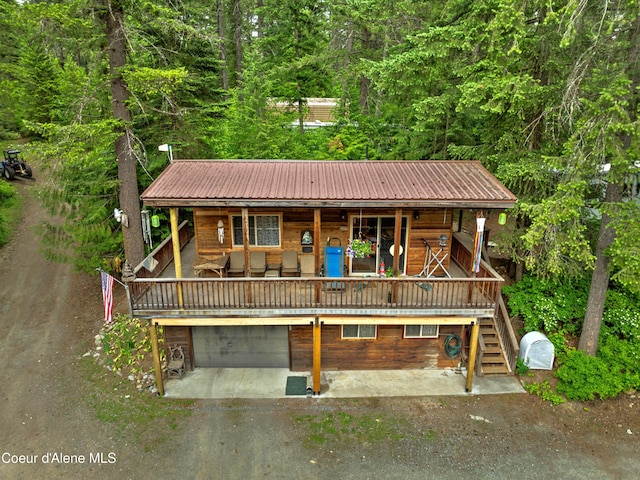 19565 N Goelzer Way, Rathdrum, ID 83858 - chalet / cabin with dirt driveway, a garage, a metal roof, a forest view, and stairs