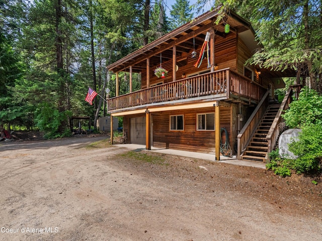19565 N Goelzer Way, Rathdrum, ID 83858 - view of front of house featuring dirt driveway, a wooden deck, a garage, and stairs