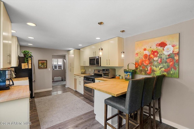 1318 N 10th St, Coeur Dalene, ID 83814 - kitchen featuring stainless steel appliances, wooden counters, dark wood-style flooring, a breakfast bar area, and a peninsula