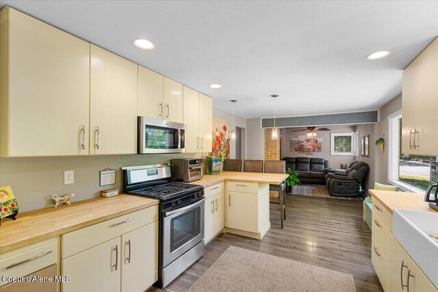 1318 N 10th St, Coeur Dalene, ID 83814 - kitchen featuring stainless steel appliances, cream cabinetry, open floor plan, a peninsula, and butcher block countertops