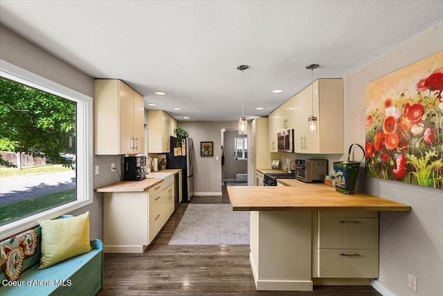 1318 N 10th St, Coeur Dalene, ID 83814 - kitchen with appliances with stainless steel finishes, cream cabinets, dark wood-type flooring, a peninsula, and hanging light fixtures