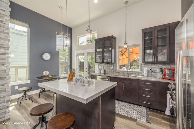 2999 N Casa Ct, Coeur Dalene, ID 83814 - kitchen with decorative backsplash, a center island, light wood finished floors, dark brown cabinetry, and a kitchen breakfast bar