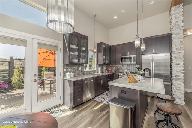 2999 N Casa Ct, Coeur Dalene, ID 83814 - kitchen with appliances with stainless steel finishes, light wood-style floors, dark brown cabinets, a kitchen breakfast bar, and tasteful backsplash