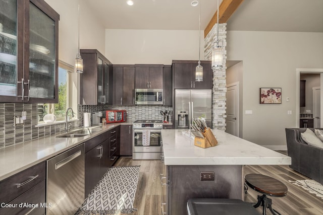 2999 N Casa Ct, Coeur Dalene, ID 83814 - kitchen featuring stainless steel appliances, dark brown cabinetry, wood finished floors, a kitchen breakfast bar, and decorative backsplash