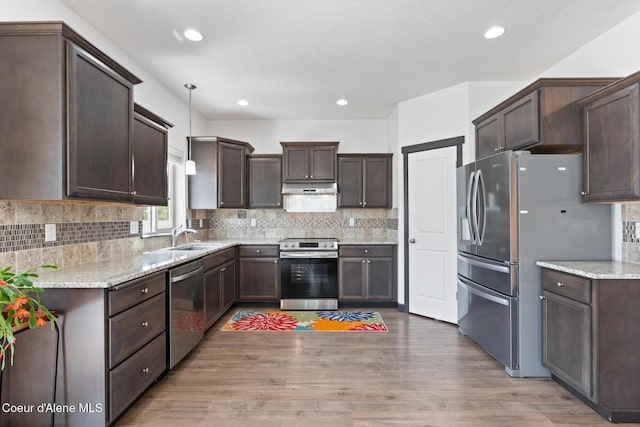6522 N Idlewood Dr, Coeur Dalene, ID 83815 - kitchen featuring appliances with stainless steel finishes, dark brown cabinets, light wood-type flooring, under cabinet range hood, and backsplash