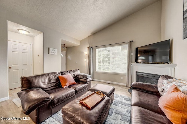 931 N Goldenrod Ct, Post Falls, ID 83854 - living area with light wood-type flooring, lofted ceiling, a textured ceiling, and a glass covered fireplace