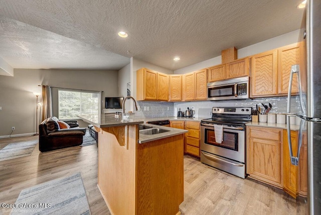 931 N Goldenrod Ct, Post Falls, ID 83854 - kitchen with appliances with stainless steel finishes, a peninsula, a textured ceiling, backsplash, and a kitchen bar