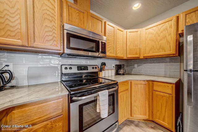 931 N Goldenrod Ct, Post Falls, ID 83854 - kitchen with appliances with stainless steel finishes, tasteful backsplash, vaulted ceiling, a textured ceiling, and recessed lighting