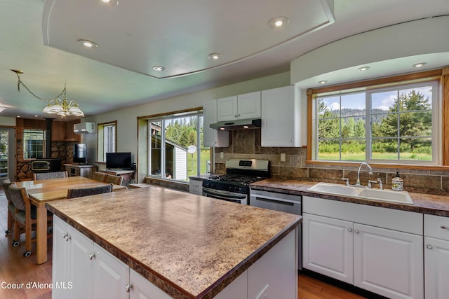 12 Otts Basin Rd, Sagle, ID 83860 - kitchen with stainless steel appliances, backsplash, light wood finished floors, white cabinetry, and under cabinet range hood