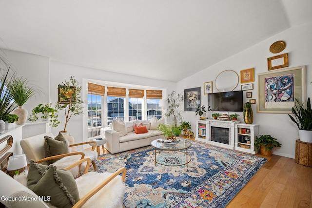 2442 N Rawhide Ridge Rd, Post Falls, ID 83854 - living room featuring vaulted ceiling, wood finished floors, and a glass covered fireplace