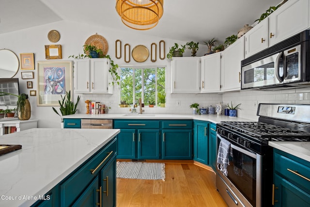 2442 N Rawhide Ridge Rd, Post Falls, ID 83854 - kitchen with stainless steel appliances, white cabinetry, decorative backsplash, light wood-style flooring, and lofted ceiling