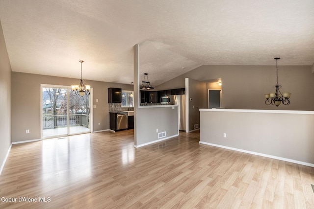 405 W 22nd Ave, Post Falls, ID 83854 - unfurnished living room featuring a chandelier, light wood-style floors, a textured ceiling, and vaulted ceiling