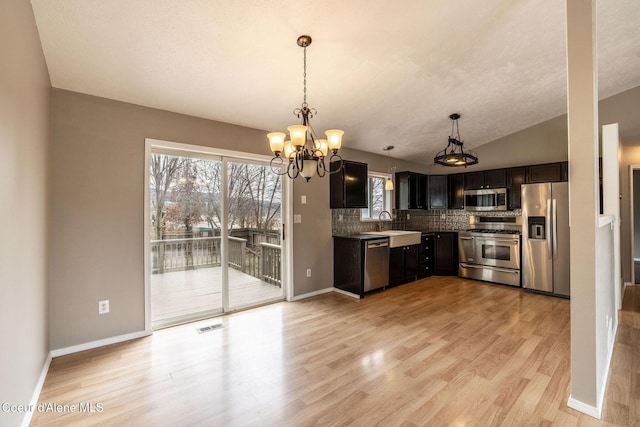 405 W 22nd Ave, Post Falls, ID 83854 - kitchen featuring appliances with stainless steel finishes, decorative backsplash, light wood finished floors, a chandelier, and plenty of natural light