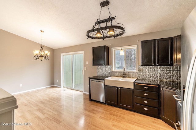 405 W 22nd Ave, Post Falls, ID 83854 - kitchen with stainless steel dishwasher, decorative backsplash, a chandelier, dark countertops, and light wood finished floors
