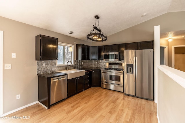 405 W 22nd Ave, Post Falls, ID 83854 - kitchen featuring appliances with stainless steel finishes, lofted ceiling, dark countertops, light wood-style flooring, and backsplash