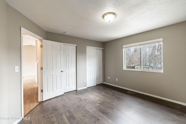 405 W 22nd Ave, Post Falls, ID 83854 - unfurnished bedroom featuring two closets, dark wood-type flooring, and a textured ceiling