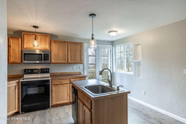 405 W 22nd Ave, Post Falls, ID 83854 - kitchen with stainless steel microwave, electric range oven, a textured wall, light wood finished floors, and a kitchen island with sink