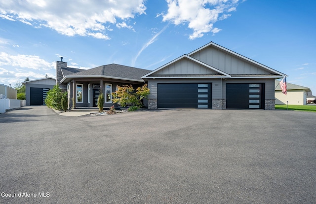 1222 W Tamarindo Ln, Hayden, ID 83835 - view of front of house with board and batten siding, stone siding, a chimney, asphalt driveway, and a garage