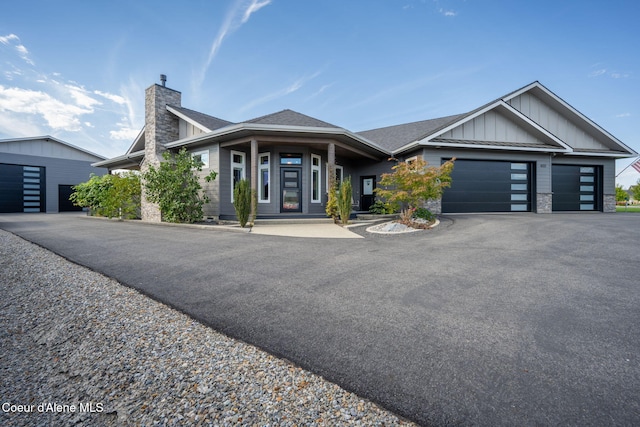 1222 W Tamarindo Ln, Hayden, ID 83835 - view of front of house with board and batten siding, a chimney, an attached garage, asphalt driveway, and roof with shingles