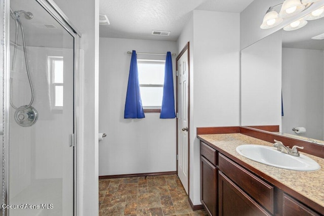 7090 N Epervier Ln, Coeur Dalene, ID 83815 - bathroom featuring vanity, a shower stall, stone finish flooring, and a textured ceiling