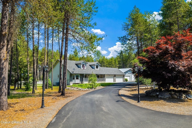 699 W Ranch Ct, Rathdrum, ID 83858 - new england style home with an attached garage, asphalt driveway, and covered porch