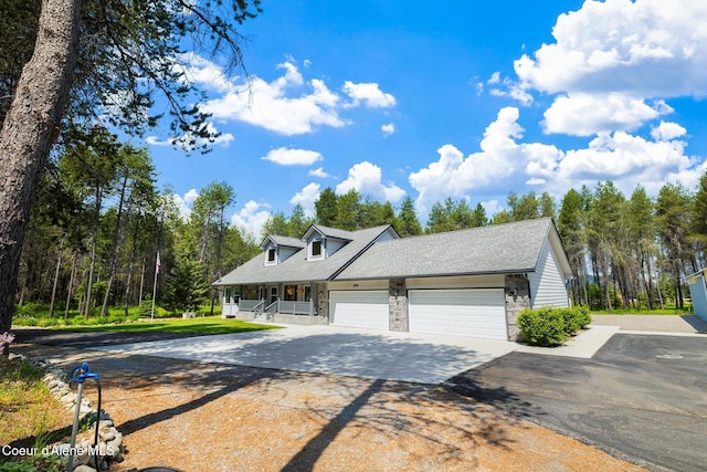 699 W Ranch Ct, Rathdrum, ID 83858 - view of front of home featuring concrete driveway, stone siding, a garage, covered porch, and roof with shingles