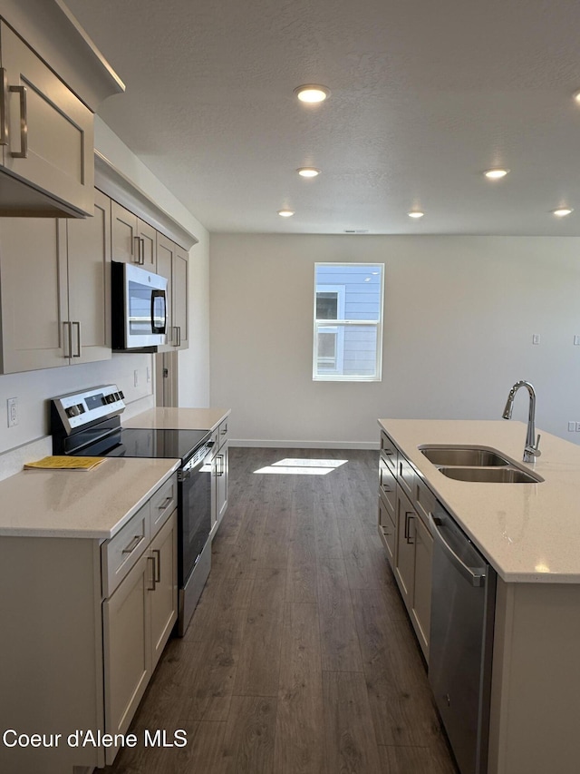 5103 E Rigel Ln, Post Falls, ID 83854 - kitchen with stainless steel appliances, dark wood-style flooring, light stone countertops, recessed lighting, and a kitchen island with sink