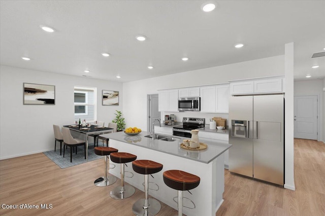 5103 E Norma Ave, Post Falls, ID 83854 - kitchen with appliances with stainless steel finishes, a kitchen breakfast bar, light wood-style flooring, white cabinetry, and recessed lighting