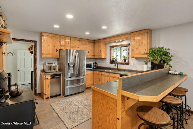 4119 Colburn Culver, Sandpoint, ID 83864 - kitchen with appliances with stainless steel finishes, dark countertops, a peninsula, recessed lighting, and a kitchen breakfast bar