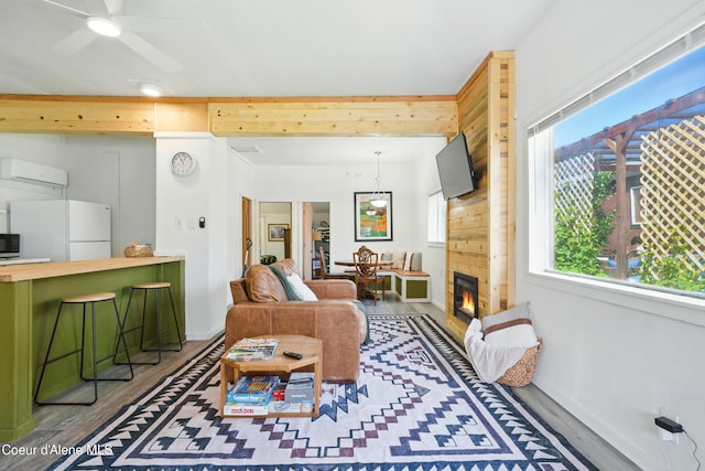 279 Birch Ave, Ponderay, ID 83852 - living room with wood finished floors, ceiling fan, a glass covered fireplace, and a wall mounted air conditioner