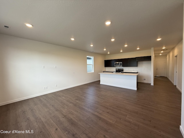 5149 E Rigel Ln, Post Falls, ID 83854 - kitchen with stainless steel microwave, open floor plan, dark wood finished floors, a kitchen island with sink, and recessed lighting