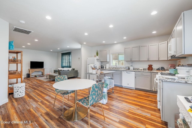 1623 E Boyd Ave, Coeur Dalene, ID 83814 - kitchen featuring white appliances, light wood-style flooring, recessed lighting, light stone countertops, and open floor plan