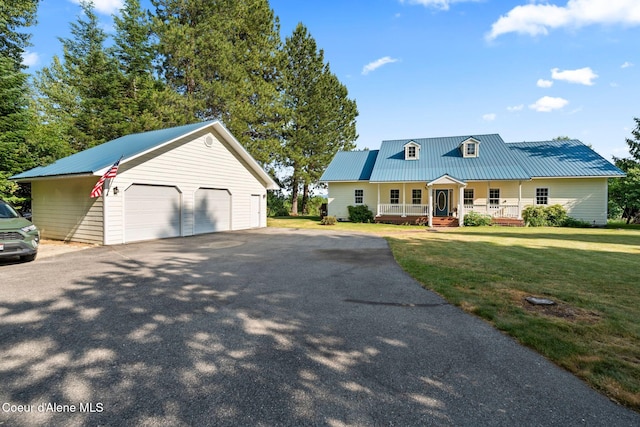 182 Sunnyside Rd, Sandpoint, ID 83864 - view of front facade featuring covered porch, a garage, an outdoor structure, a front yard, and a metal roof