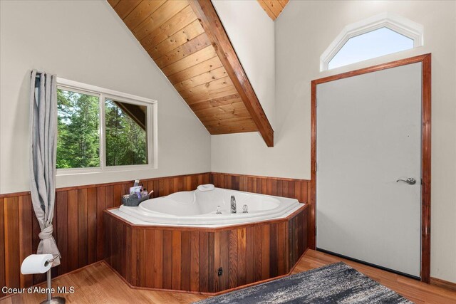 299 Oak Ter, Cocolalla, ID 83813 - bathroom with lofted ceiling, a tub with jets, a wainscoted wall, and wood finished floors
