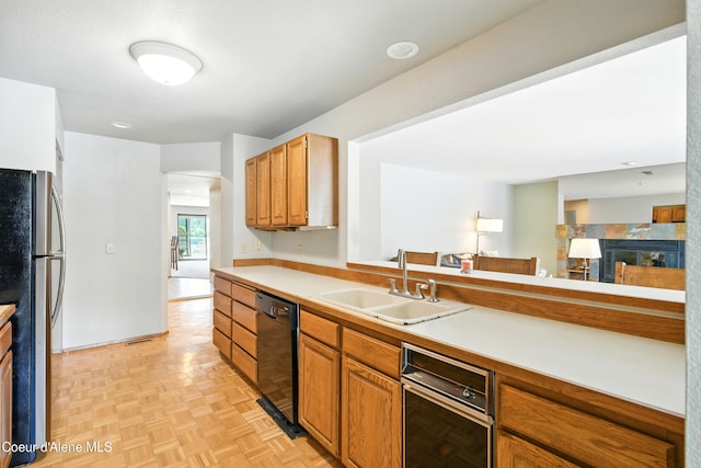 204 E 1st Ave E # 4, Post Falls, ID 83854 - kitchen featuring black dishwasher, freestanding refrigerator, light countertops, brown cabinetry, and a fireplace