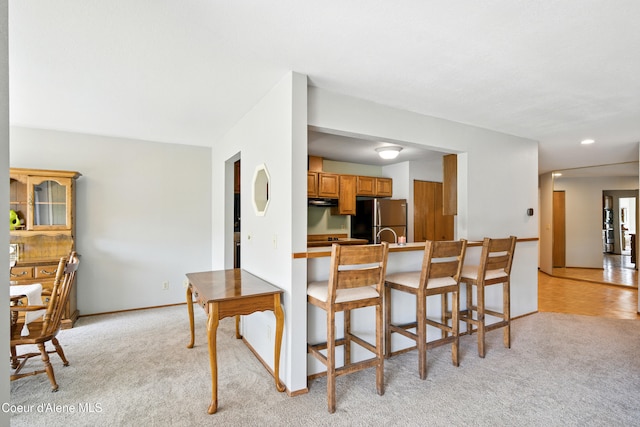 204 E 1st Ave E # 4, Post Falls, ID 83854 - kitchen with freestanding refrigerator, light colored carpet, brown cabinets, a breakfast bar area, and recessed lighting