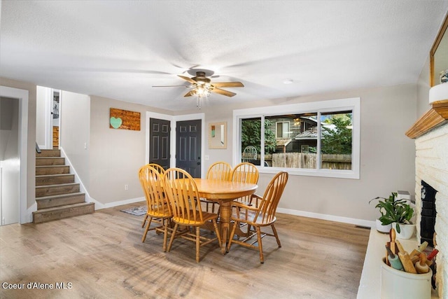 3212 N 7th St, Coeur Dalene, ID 83815 - dining area with wood finished floors, stairway, a ceiling fan, and a fireplace with raised hearth