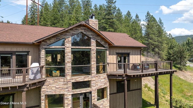 602 Country Club Ln, Pinehurst, ID 83850 - rear view of property featuring a chimney, stone siding, a shingled roof, and a deck