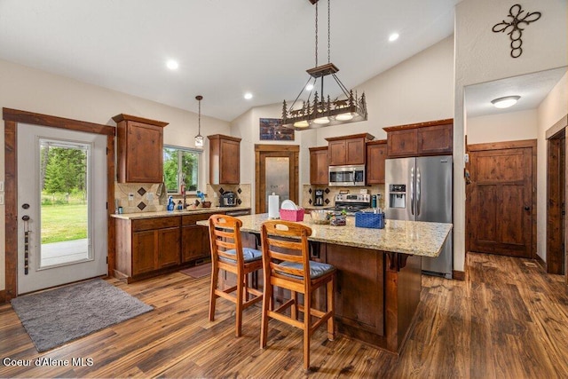 695 W Keva Ln, Athol, ID 83801 - kitchen featuring appliances with stainless steel finishes, vaulted ceiling, dark wood finished floors, decorative backsplash, and a center island