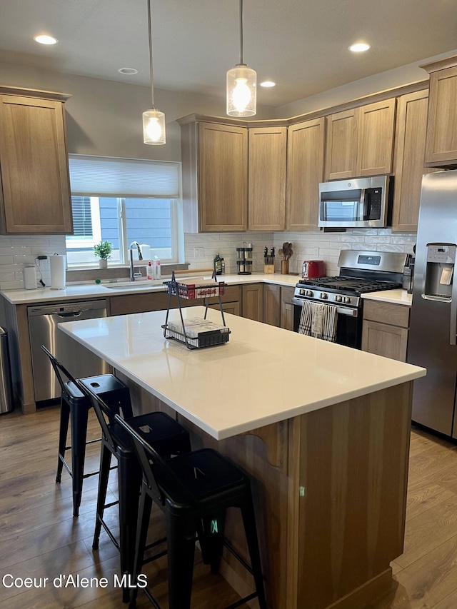 4263 N Donovan Ln, Post Falls, ID 83854 - kitchen featuring appliances with stainless steel finishes, decorative backsplash, a kitchen island, a breakfast bar, and light wood finished floors
