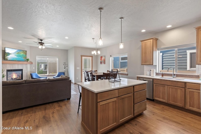 4263 N Donovan Ln, Post Falls, ID 83854 - kitchen featuring stainless steel dishwasher, a textured ceiling, a breakfast bar area, a tiled fireplace, and light countertops