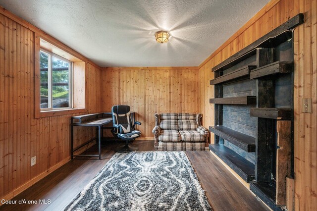 9067 W Coeur D Alene Dr, Spirit Lake, ID 83869 - living area featuring wood finished floors, wooden walls, a fireplace, and a textured ceiling