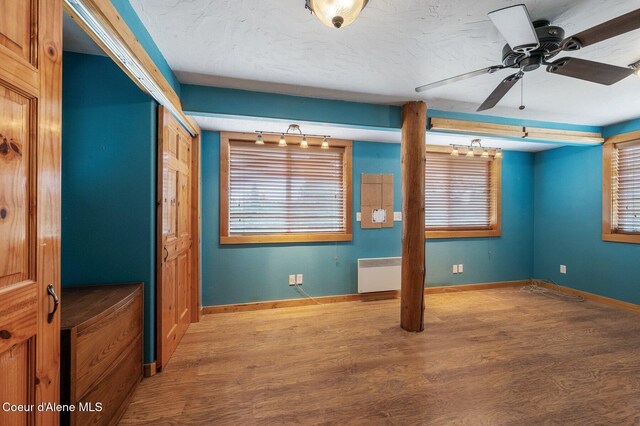 9067 W Coeur D Alene Dr, Spirit Lake, ID 83869 - empty room with radiator, wood finished floors, a ceiling fan, and healthy amount of natural light