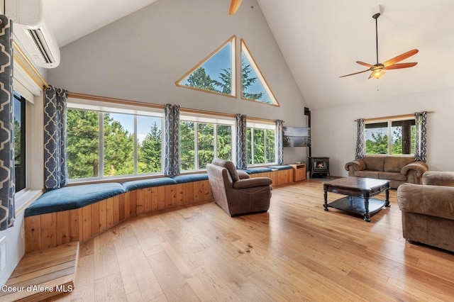 9067 W Coeur D Alene Dr, Spirit Lake, ID 83869 - living room with a wall mounted AC, high vaulted ceiling, a wood stove, ceiling fan, and light wood-style flooring